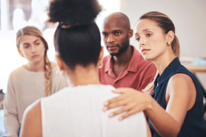 Compassionate people in group therapy comforting a new enrollee at an opioid rehab center