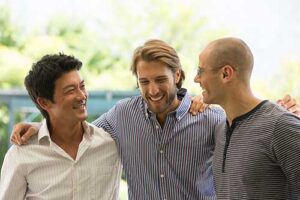 a group of men in a men's rehab program hug and smile