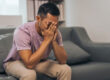 person on couch with face in hands struggling with alcohol withdrawal