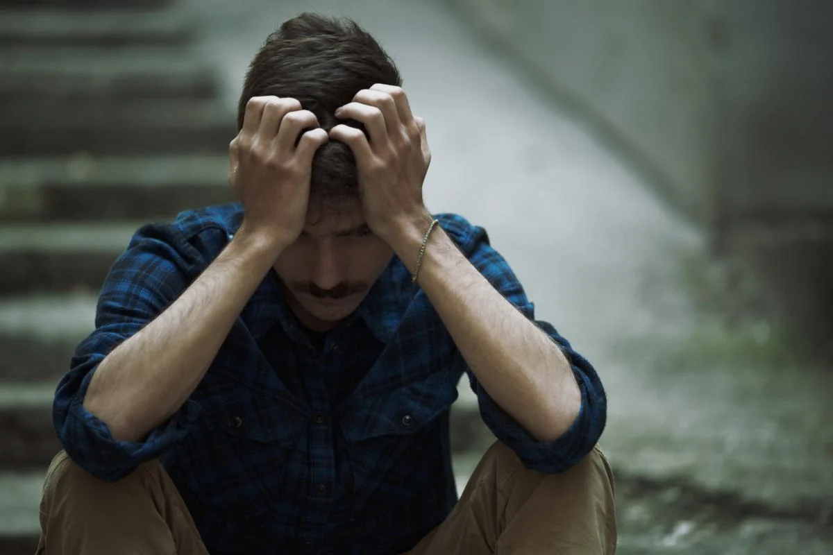 Man sitting on steps with his head in his hands wondering how to overcome cocaine addiction