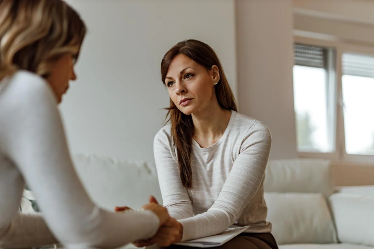 therapist holding the hands of a patient discussing MAT for alcohol