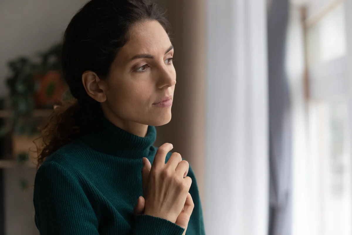 woman looking out window in addiction therapy program thinking about vulnerability and SUD treatment