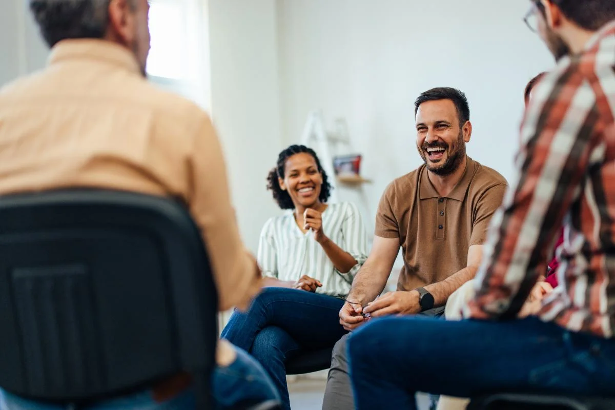 Individuals smiling in a group therapy setting learning what is group therapy