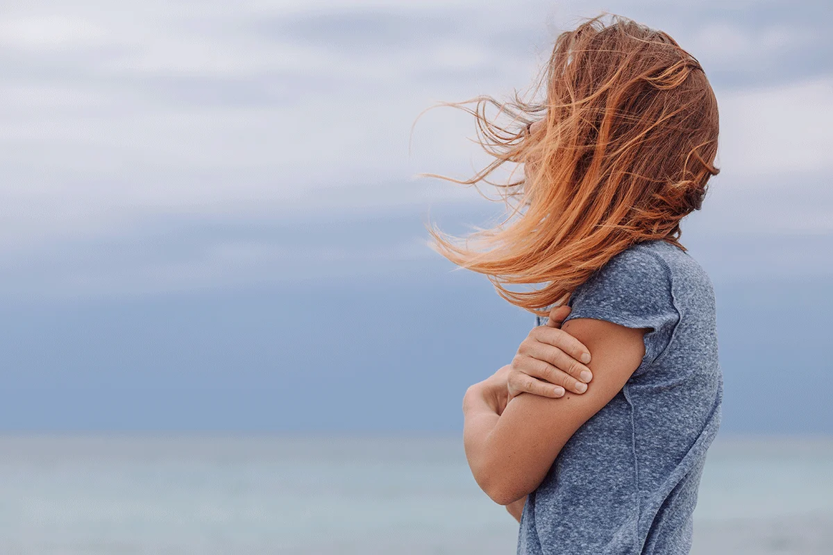 woman on beach with windswept hair contemplating treatment for cocaine addiction