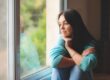 Woman sitting quietly by a window, reflecting during early recovery from alcohol withdrawal symptoms